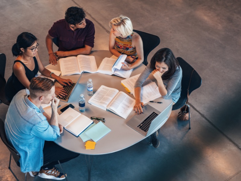 view of students working at a table - surveys for students post